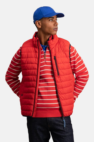 Veste sans manches rouge by FYNCH-HATTON, portée sur un pull rayé, avec une casquette bleue.