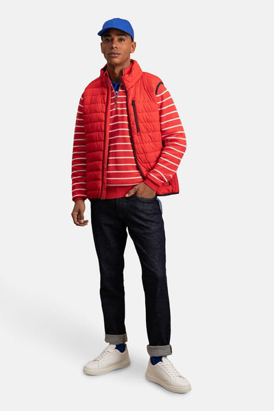 Veste sans manches rouge de FYNCH-HATTON avec fermeture éclair et matelassage visible, portée avec un pull rayé.
