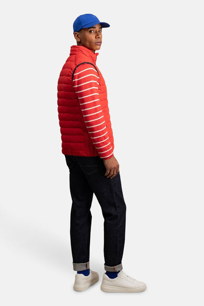 Veste sans manches rouge de FYNCH-HATTON, matelassée avec un t-shirt rayé, un jean bleu marine et des baskets blanches.
