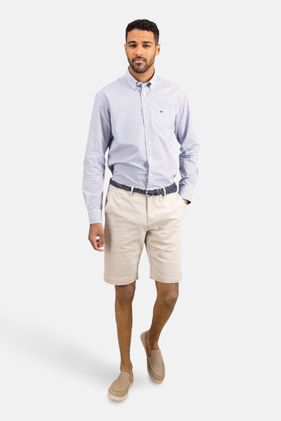 Chemise à manches longues imprimée par FYNCH-HATTON, portée avec un short beige, une ceinture tressée bleue et des chaussures décontractées.