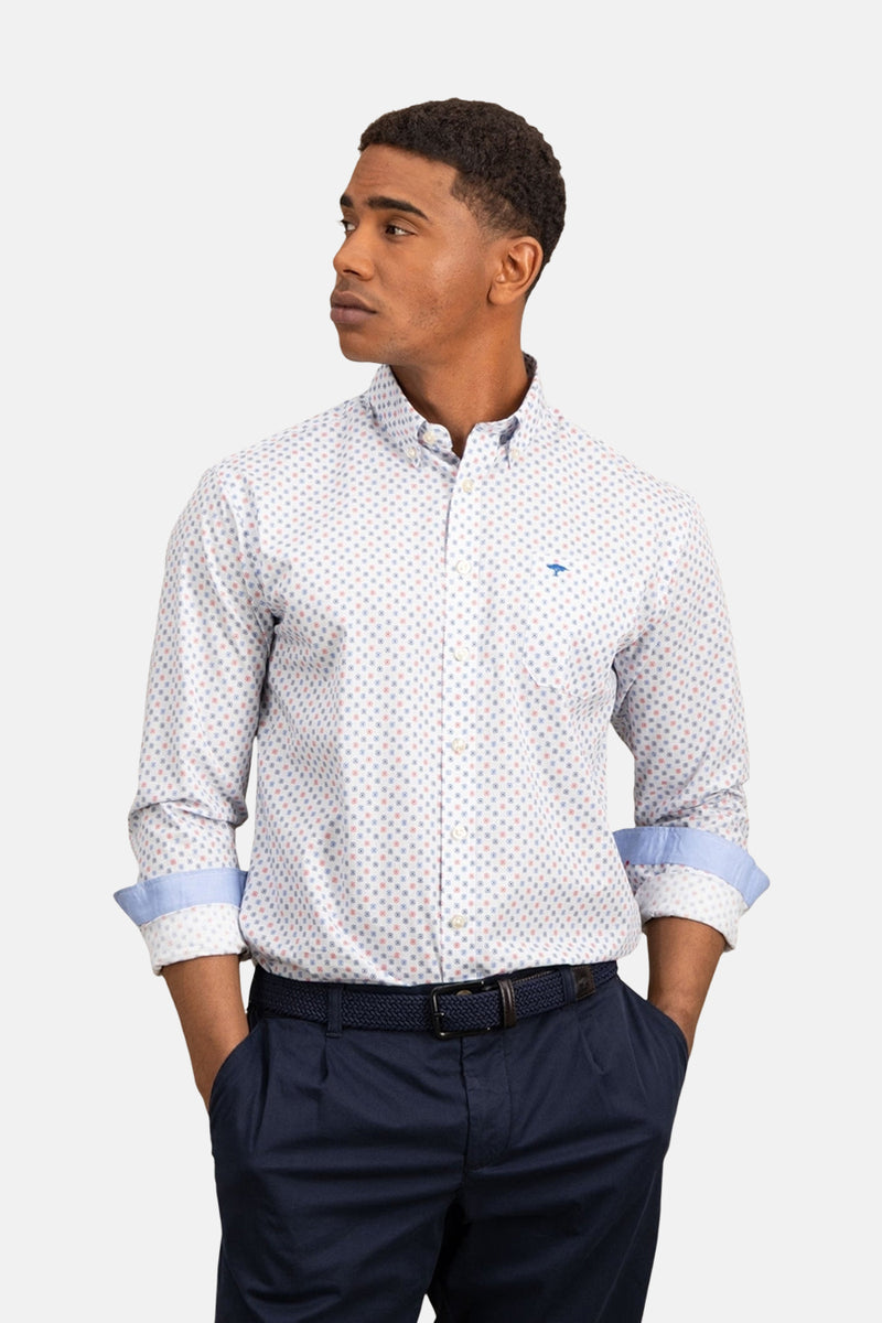 Chemise à manches longues imprimée, bleu, de FYNCH-HATTON, avec revers de manche bleus et pantalon marine porté avec une ceinture tressée.
