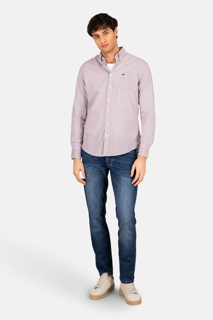 Chemise rouge à manches longues de FYNCH-HATTON, avec motif imprimé, portée avec un jean bleu et des baskets beiges.