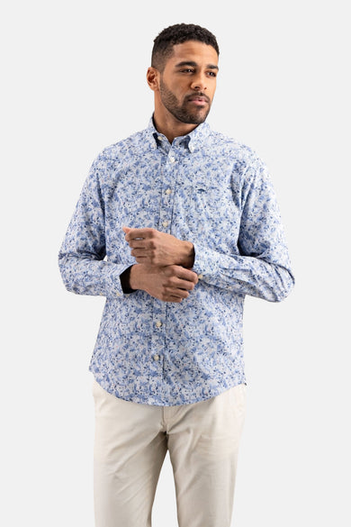 Blauwe lange mouw chemise van FYNCH-HATTON met bloemmotief, gedragen met een lichte broek en mocassins.