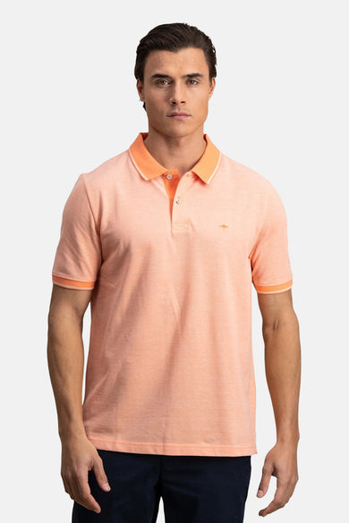 Oranje poloshirt met korte mouwen van FYNCH-HATTON, gedragen met een opgerolde marineblauwe broek en witte sneakers.