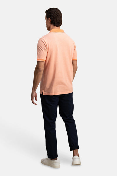 Polo orange à manches courtes de FYNCH-HATTON, porté avec un pantalon bleu marine retroussé et des baskets blanches.