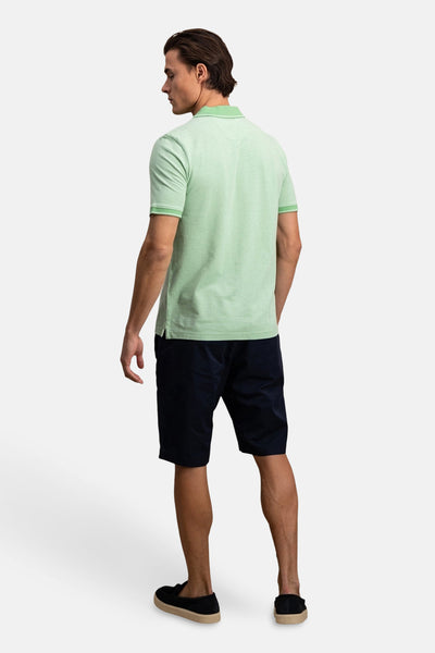 Polo à manches courtes vert de FYNCH-HATTON, vu de dos, porté avec un short bleu marine et des mocassins noirs.
