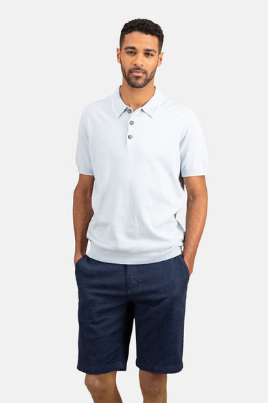 Lichtblauw poloshirt met korte mouwen van FYNCH-HATTON, gedragen met een marineblauwe korte broek en witte sneakers, achterzicht.