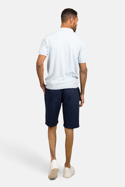 Polo à manches courtes bleu clair de FYNCH-HATTON, porté avec un short bleu marine et des baskets blanches, vue de dos.