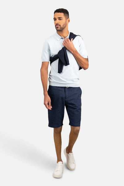 Polo à manches courtes bleu clair de FYNCH-HATTON, porté avec un pull noué et un short en jean.