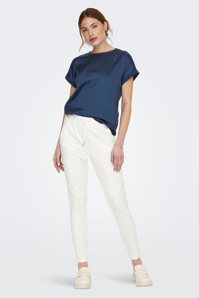 Chino écru de ONLY®, porté avec un t-shirt bleu marine et des chaussures neutres.