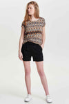 Korte zwarte short van ONLY, gedragen met een T-shirt met geometrische print en witte sneakers
