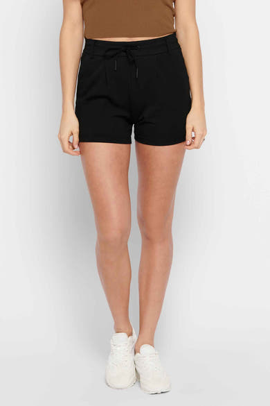 Korte zwarte short van ONLY, gedragen met een bruine top en witte sneakers.