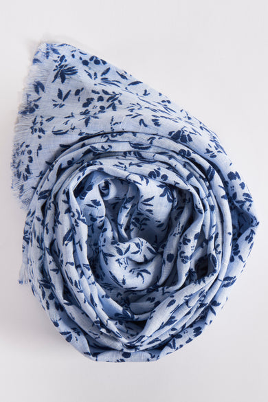 Blauwe sjaal van FYNCH-HATTON, bedrukt met marineblauwe bloemenpatronen, om zichzelf heen gewikkeld.