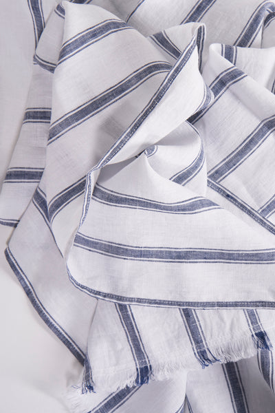 Foulard blanc à rayures bleues par FYNCH-HATTON, avec des détails de texture lin et ourlets effilochés.
