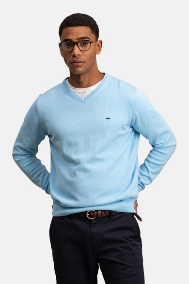 Pull à col en V bleu de FYNCH-HATTON, porté avec un pantalon et une ceinture marron.