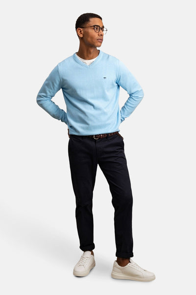 Pull à col en V bleu de FYNCH-HATTON avec pantalon bleu marine et chaussures blanches.