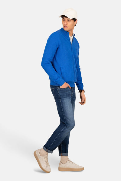 Blauwe bodywarmer van FYNCH-HATTON met ritssluiting, gedragen met een spijkerbroek en beige sneakers.