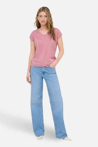 Top uni manches courtes rose de ONLY, porté avec un jean large bleu et des escarpins blancs.