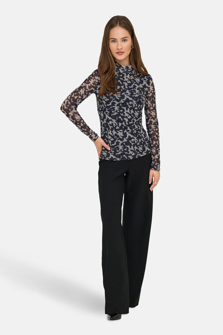 Multikleuren coltrui van ONLY, met abstract patroon, gedragen met een zwarte broek met wijde pijpen.