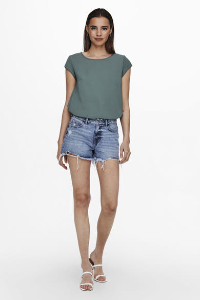 Blouse verte à manches courtes par ONLY, portée avec un short en jean taille haute et des sandales blanches.