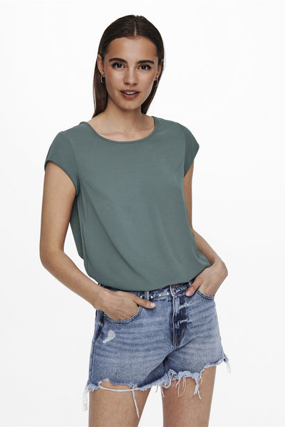 Blouse à manches courtes verte de ONLY, portée avec un short en jean délavé et déchiré.
