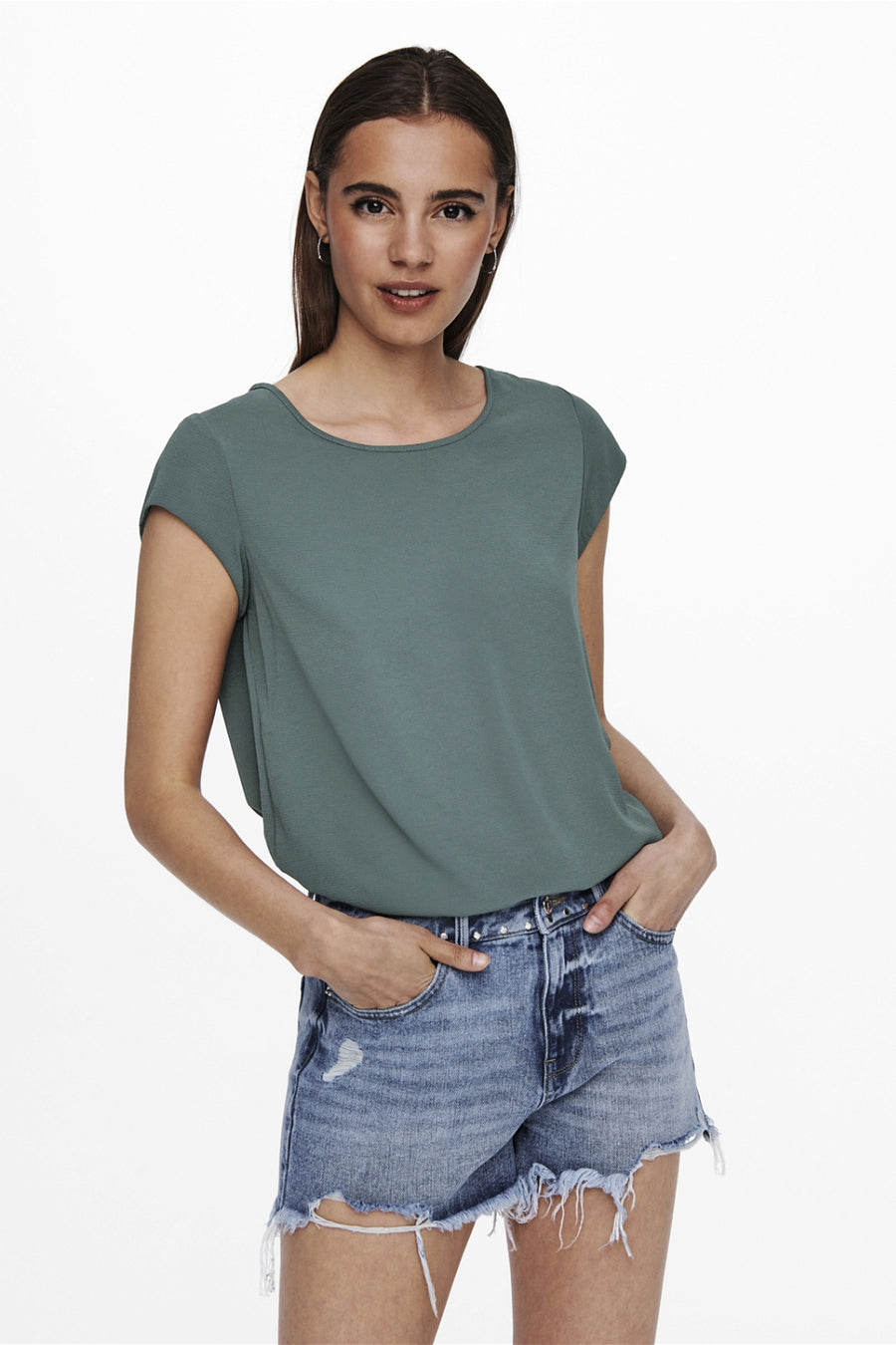 Blouse à manches courtes verte de ONLY, portée avec un short en jean délavé et déchiré.