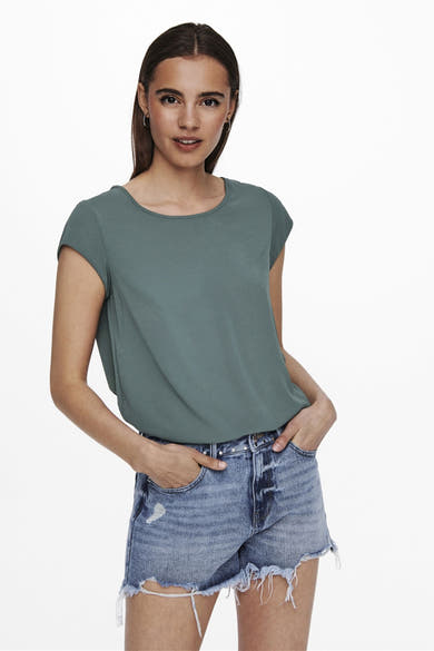 Blouse à manches courtes verte de ONLY®, portée avec un short en jean bleu délavé.