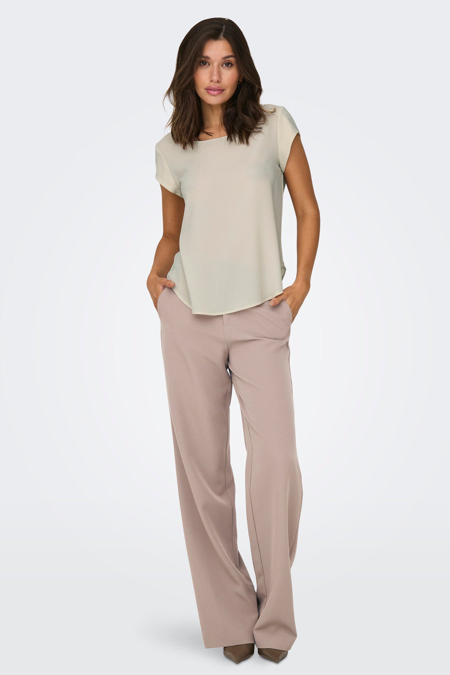 Chemisier beige à manches courtes de ONLY, porté avec un pantalon coupe ample.
