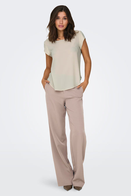 Chemisier beige à manches courtes de ONLY, porté avec un pantalon tailleur rose poudré.