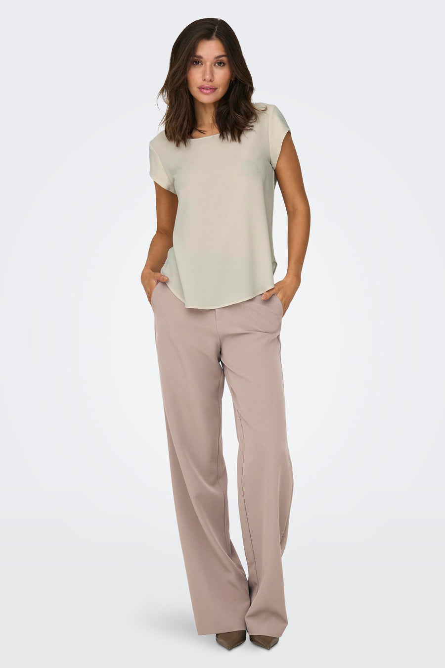 Chemisier beige à manches courtes de ONLY, porté avec un pantalon tailleur rose poudré.