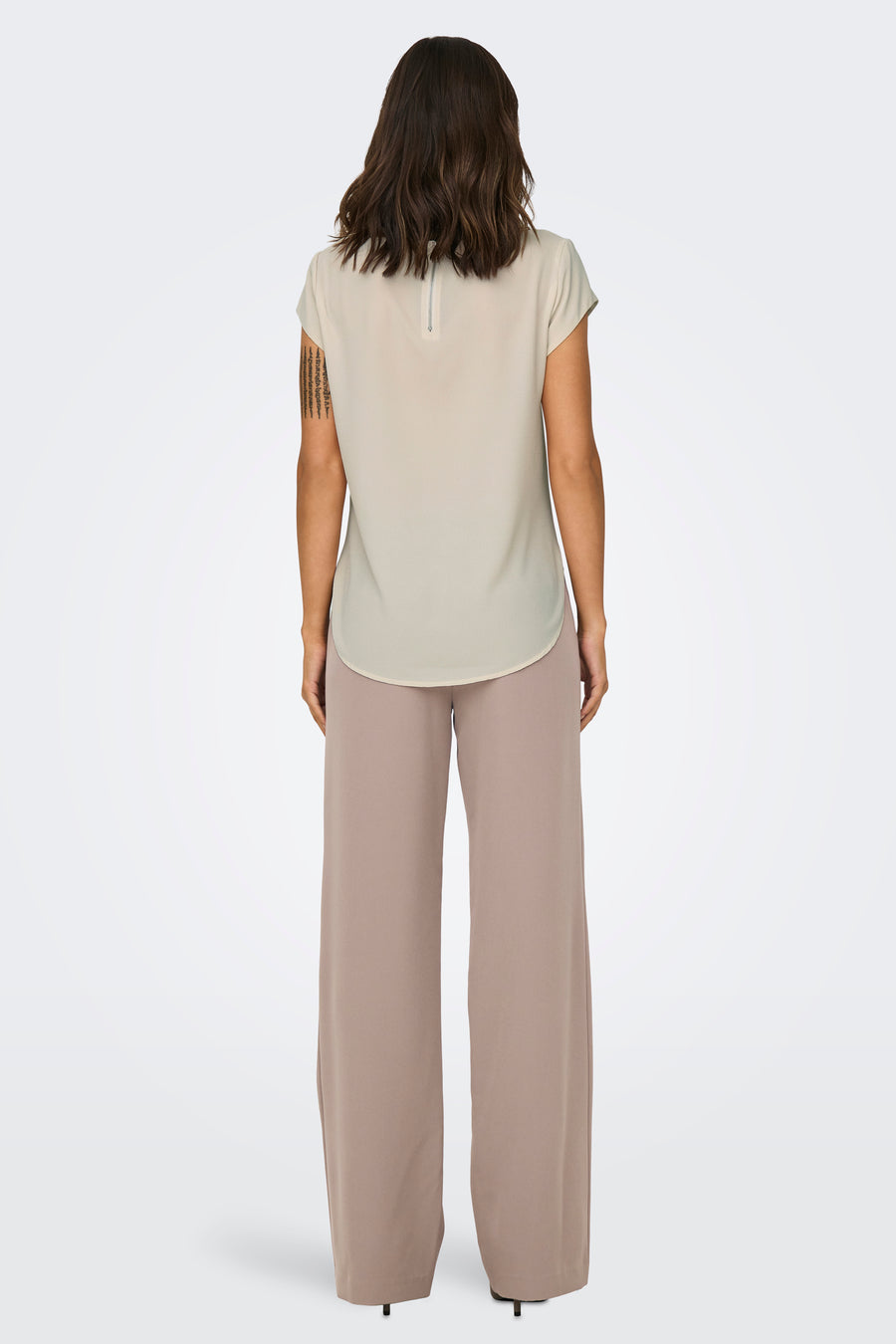 Chemisier beige à manches courtes de ONLY, avec fermeture éclair au dos et porté avec un pantalon beige large.