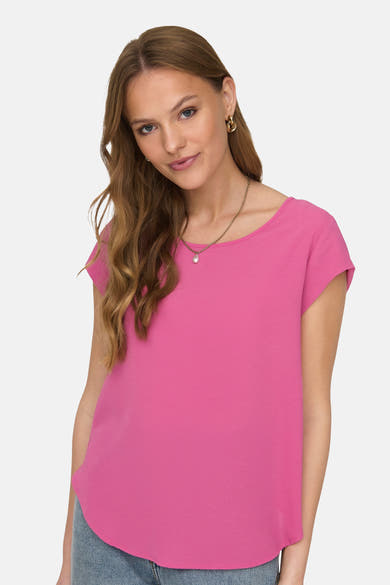 Blouse rose à manches courtes de ONLY, portée avec un collier délicat et des boucles d'oreilles dorées.