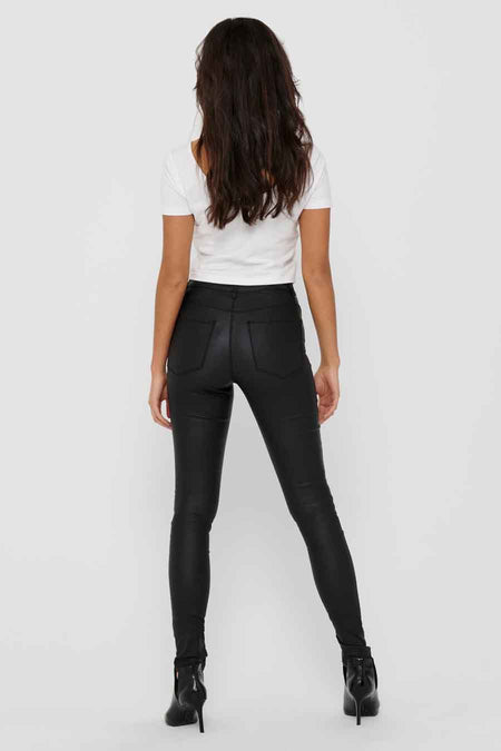 Pantalon noir moulant de ONLY, porté avec un t-shirt blanc et des bottines à talons hauts.