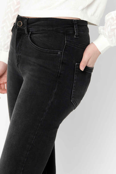 Zwarte skinny jeans van ONLY, gedragen met een witte trui met pofmouwen en een zichtbare knoop.