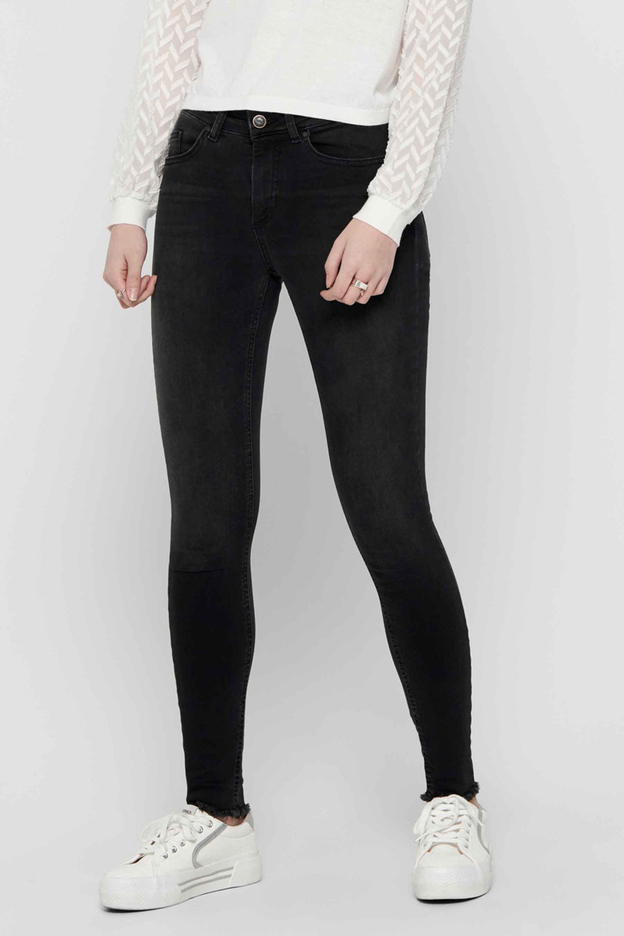 Skinny jeans van zwart denim van ONLY, gedragen met een wit blouse met patroon.