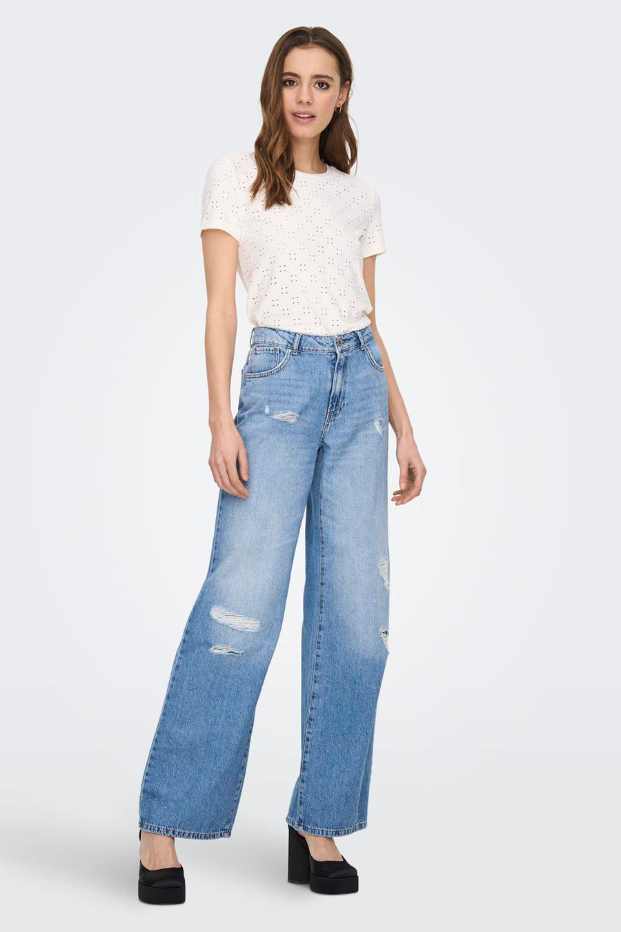 Top blanc uni manche courte de JDY, porté avec un jean large délavé et des chaussures à talons plateforme noirs.
