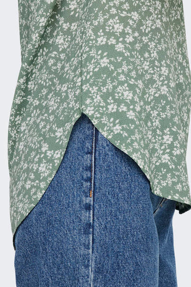 Blouse à manches courtes fleurie verte et blanche de ONLY®, portée avec un jean bleu.