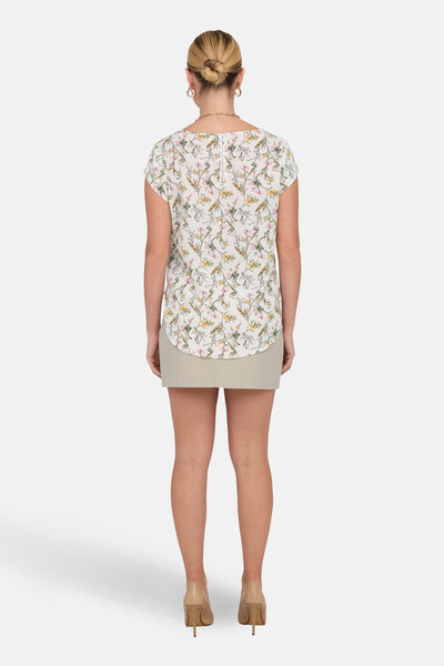 Bloes met korte mouwen en bloemenprint van ONLY®, gedragen met een beige minirok en nude pumps.
