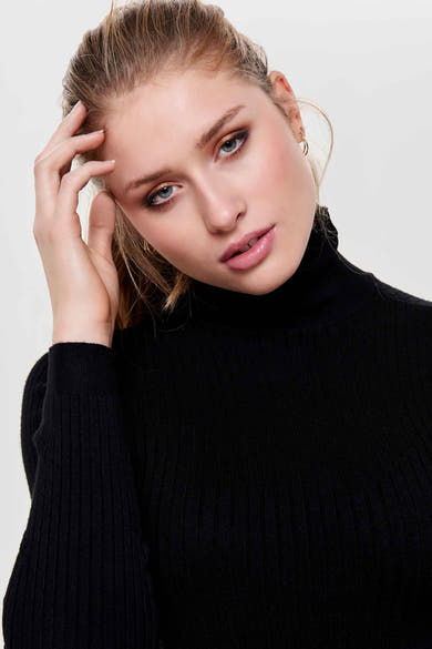 Pull noir de ONLY, en maille côtelée fine, porté avec des boucles d'oreilles dorées.

