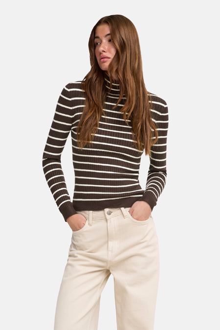 Pull à col roulant ONLY® marron à rayures écrues, porté avec un pantalon écru.