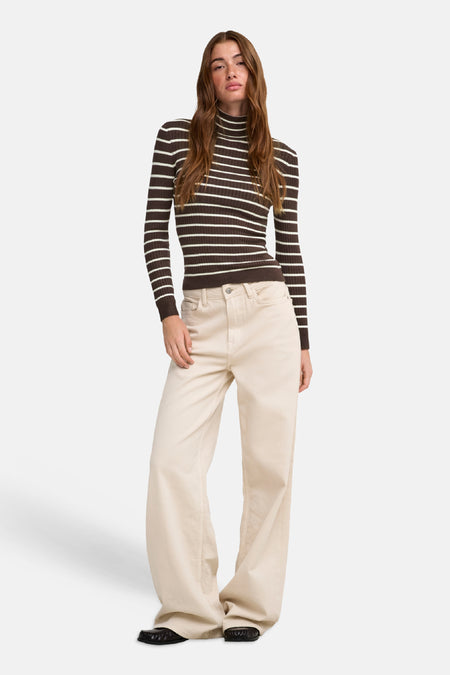 Pull à col roulé marron à rayures blanches ONLY® porté par une femme.
