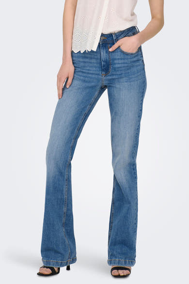 JDY blauwe flared jeans, gedragen met een witte kanten top en zwarte hak sandalen.