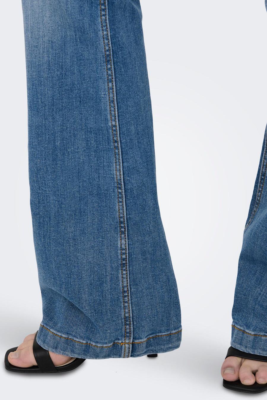 JDY blauwe flared jeans, zichtbare stikseldetails en gestikte zoom, gedragen met zwarte muiltjes.