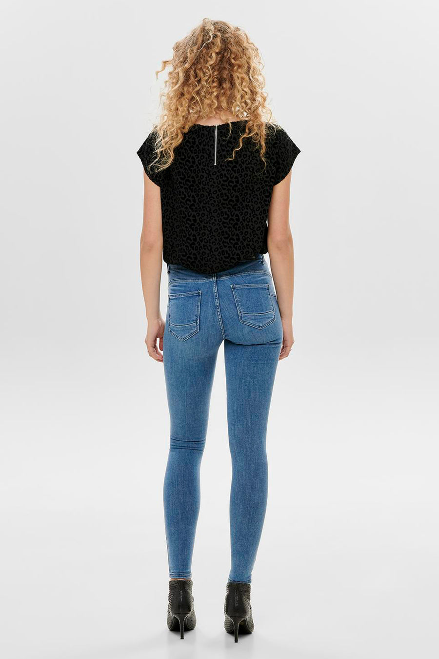 Jean skinny bleu de ONLY, coupe moulante, avec des poches arrière et porté avec un top à imprimé léopard.
