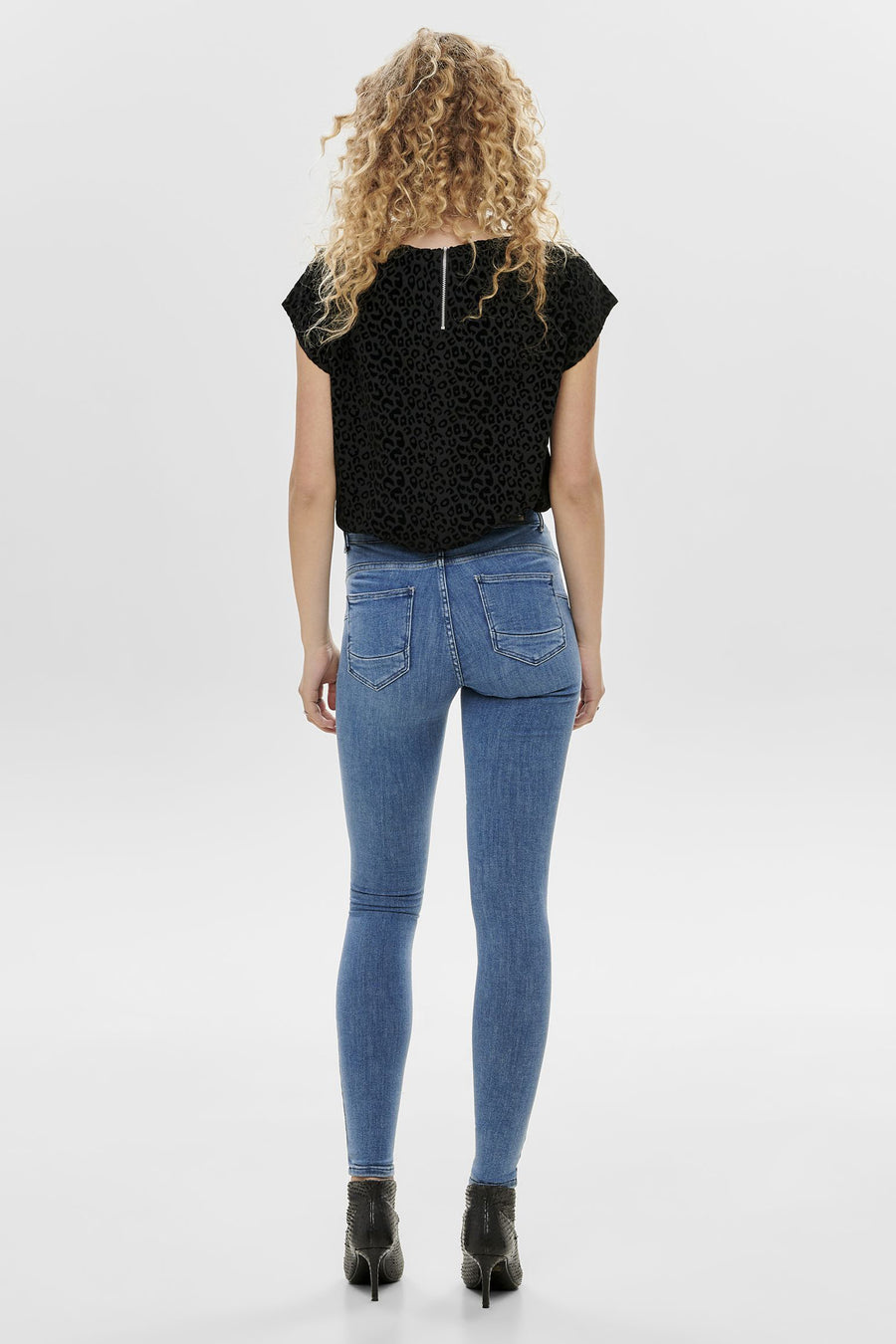 Blauwe skinny jeans van ONLY®, gedragen met een top met luipaardprint en naaldhak enkellaarsjes.