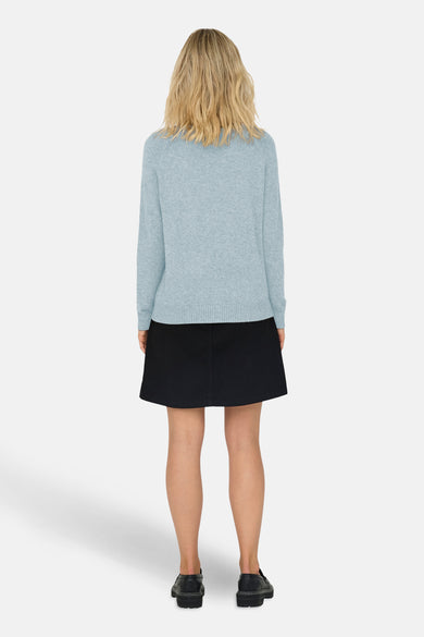 Pull à col rond bleu de ONLY®, porté avec une jupe noire et des chaussures plates.