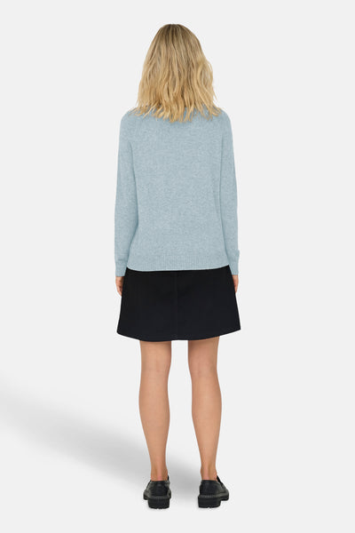 Pull à col rond bleu de ONLY®, porté avec une jupe noire et des chaussures plates.