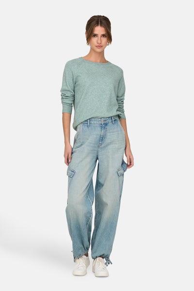 Groene trui met ronde hals van ONLY, gedragen met een wijde lichtblauwe cargobroek en witte sneakers.