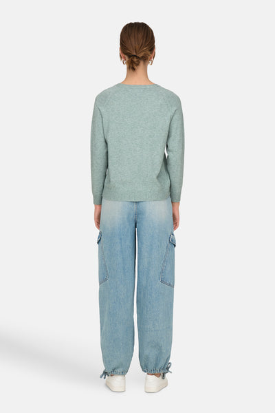 Groene trui met ronde hals van ONLY, gedragen met een wijde jeans en witte sneakers.