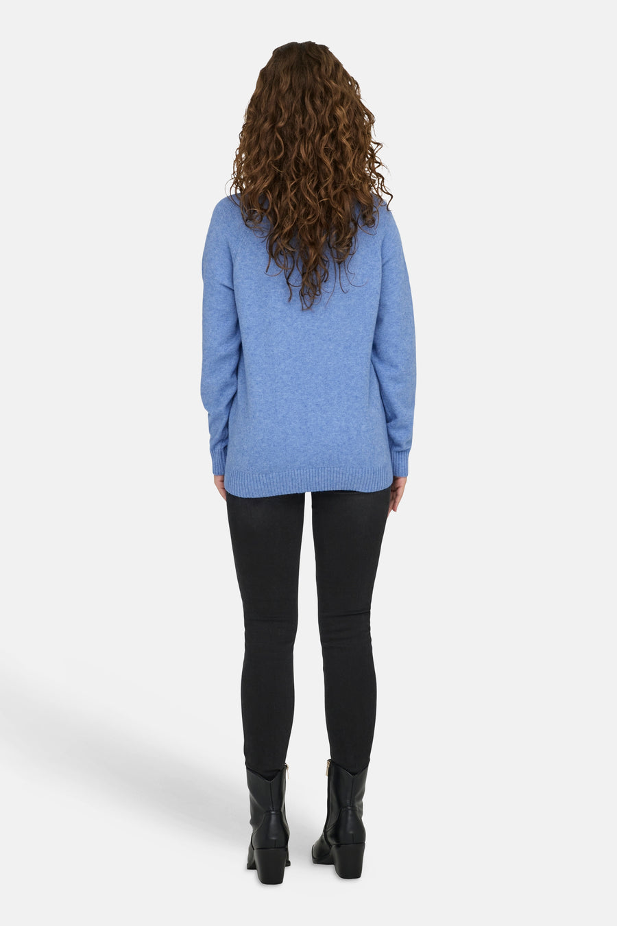 Pull à col rond bleu de ONLY®, porté avec un pantalon noir et des bottes en cuir.